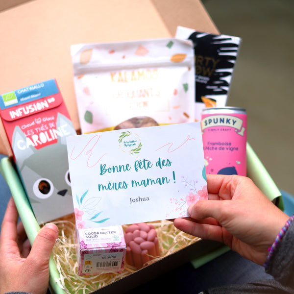 Individu ouvrant la box fêtes des mères et tenant une carte cadeau dans sa main